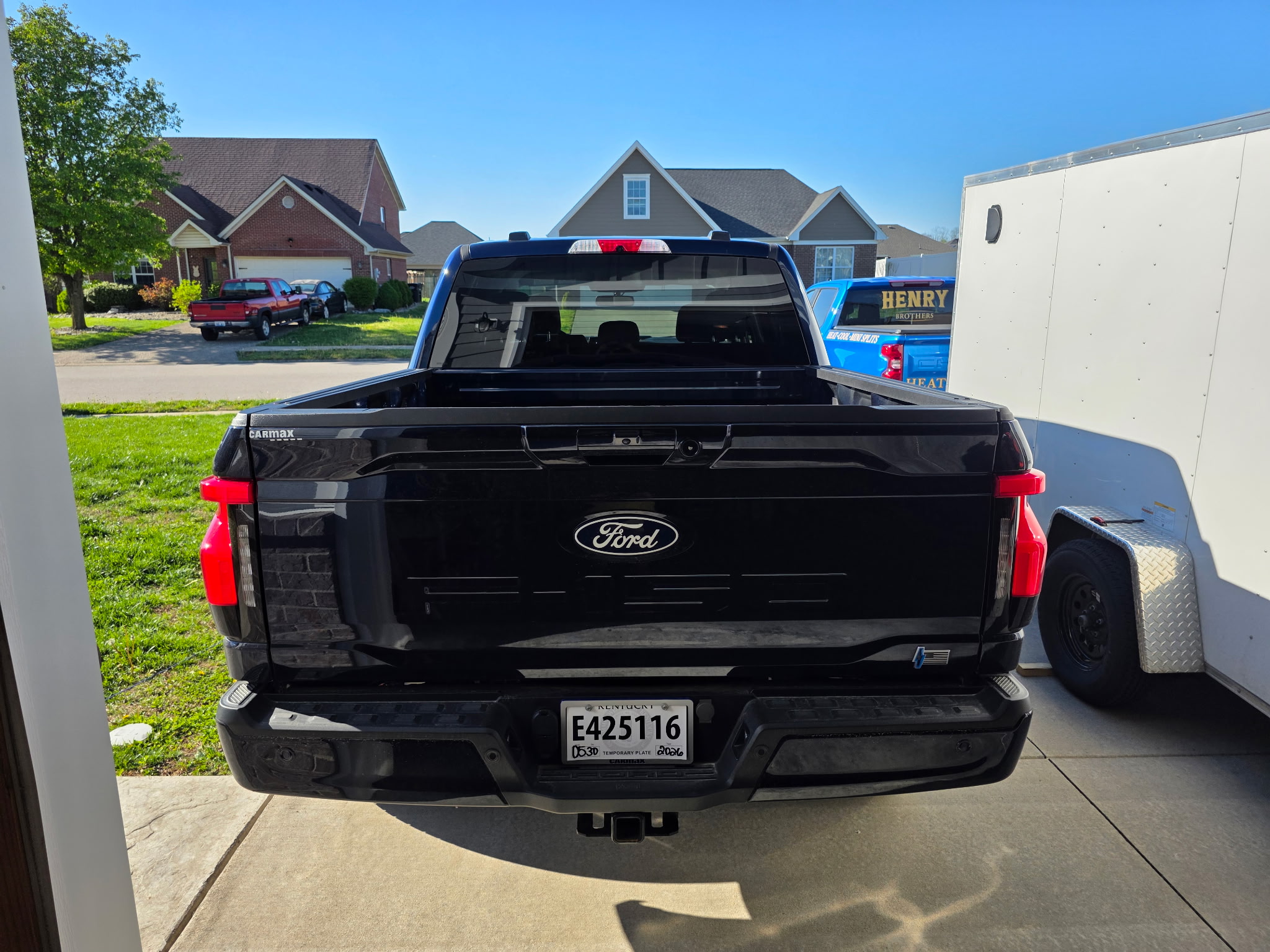 Henry Brothers HVAC branded van in background behind Ford truck at neighborhood job site
