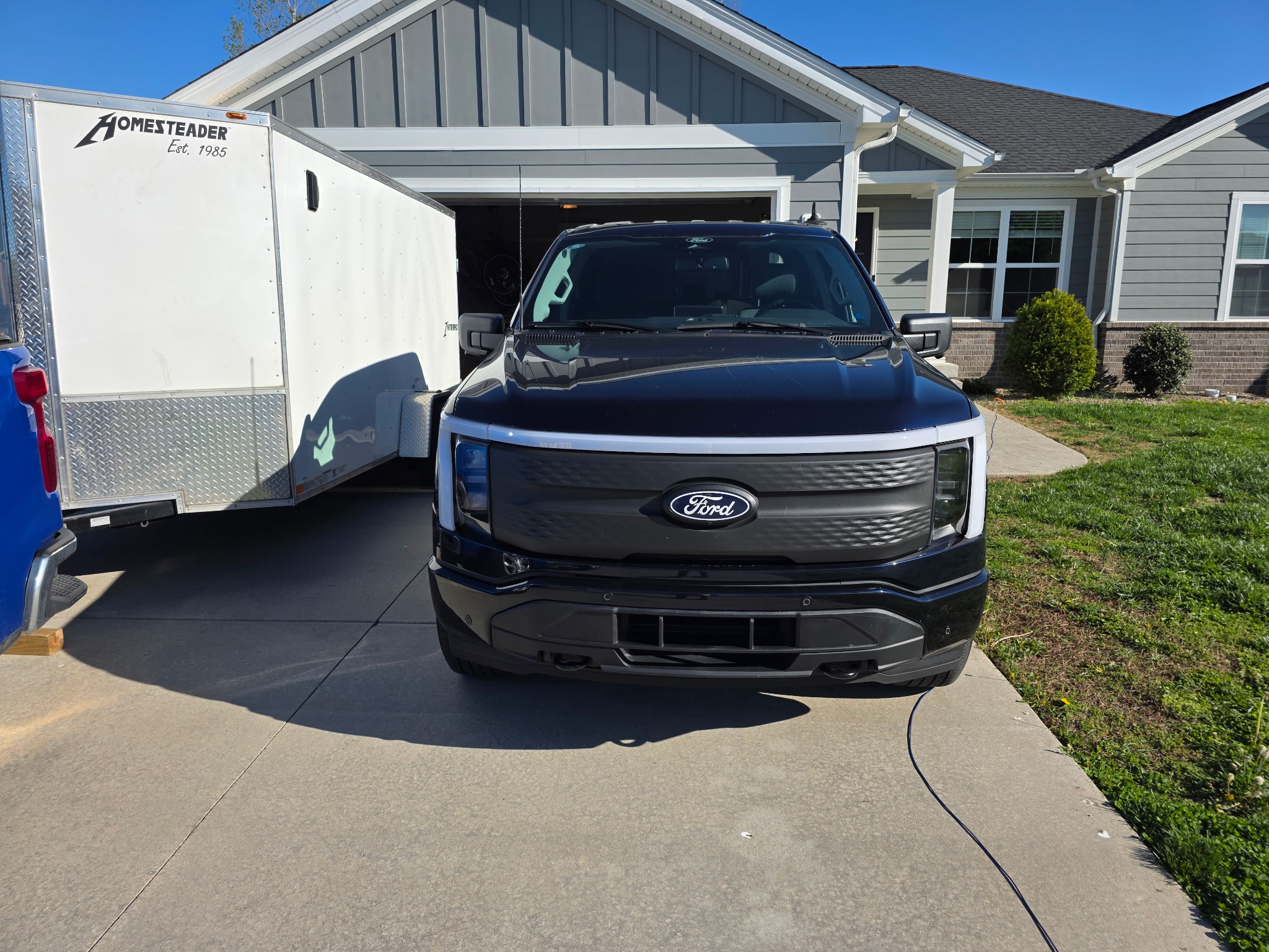 Henry Brothers HVAC Ford F-150 Lightning electric truck with work trailer at customer home