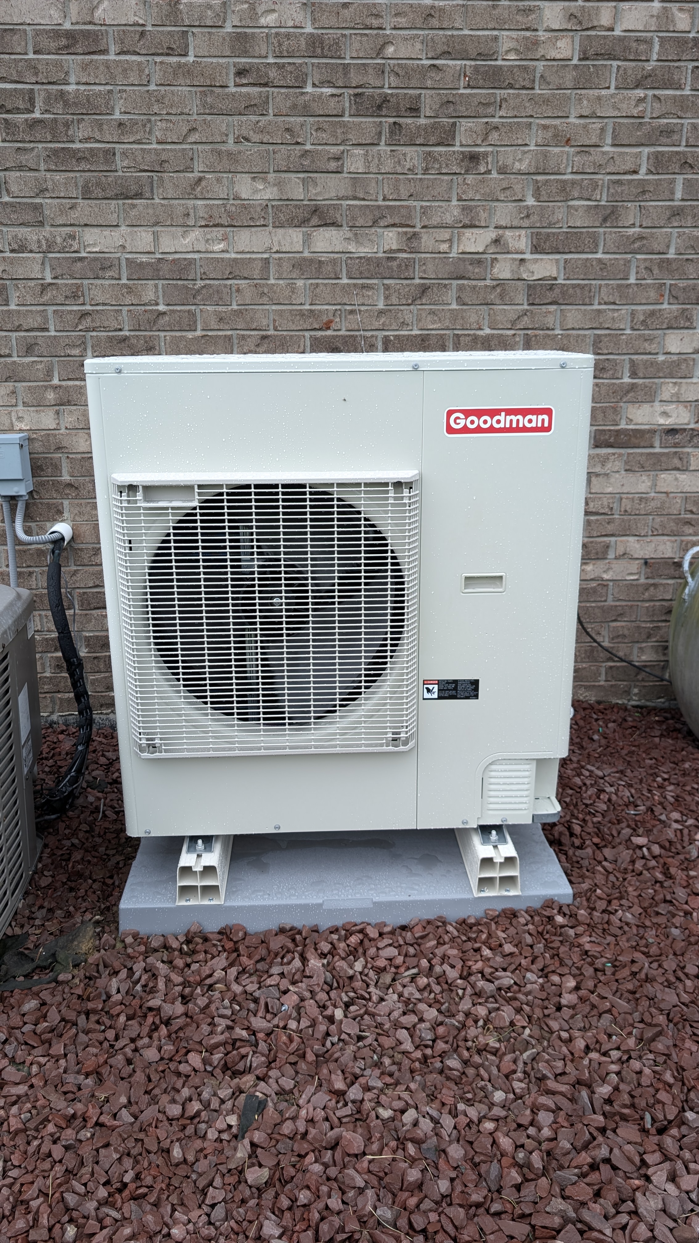 Goodman mini-split outdoor condenser installed on pad against brick wall Clark County Indiana