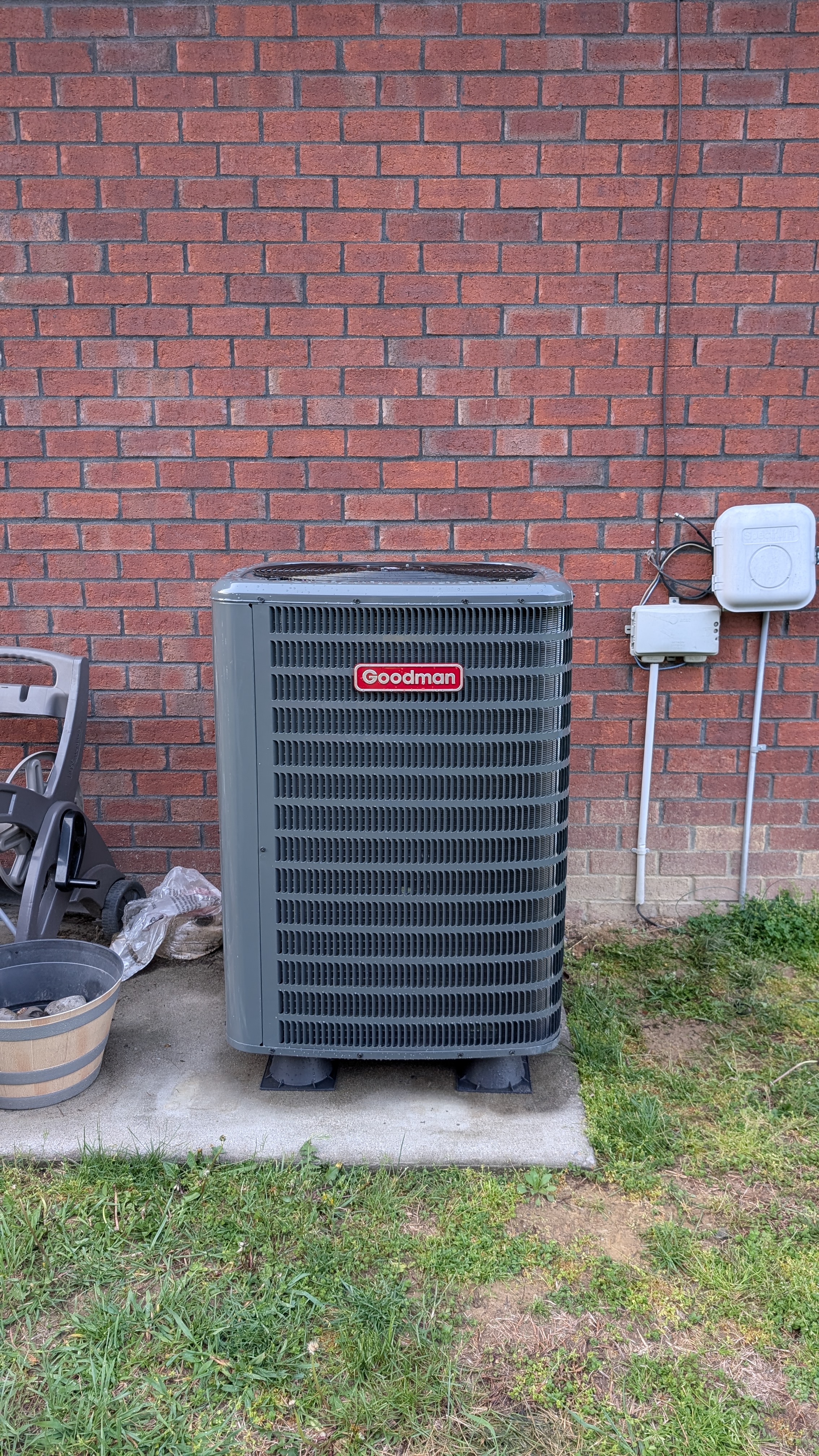 Goodman central air condenser unit installed on pad against brick exterior, Clark County Indiana