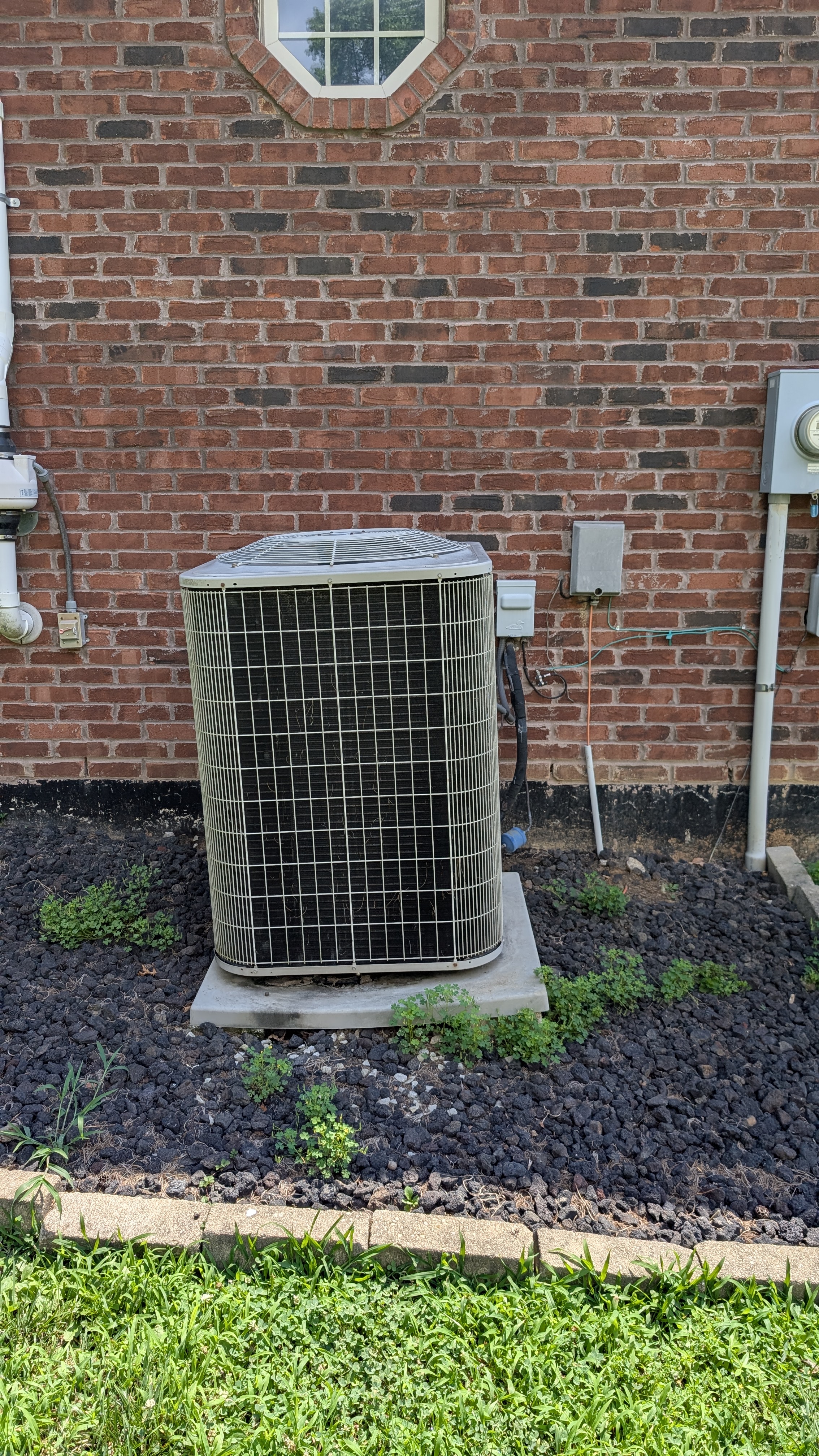Old central AC condenser unit against brick wall before removal Memphis Indiana
