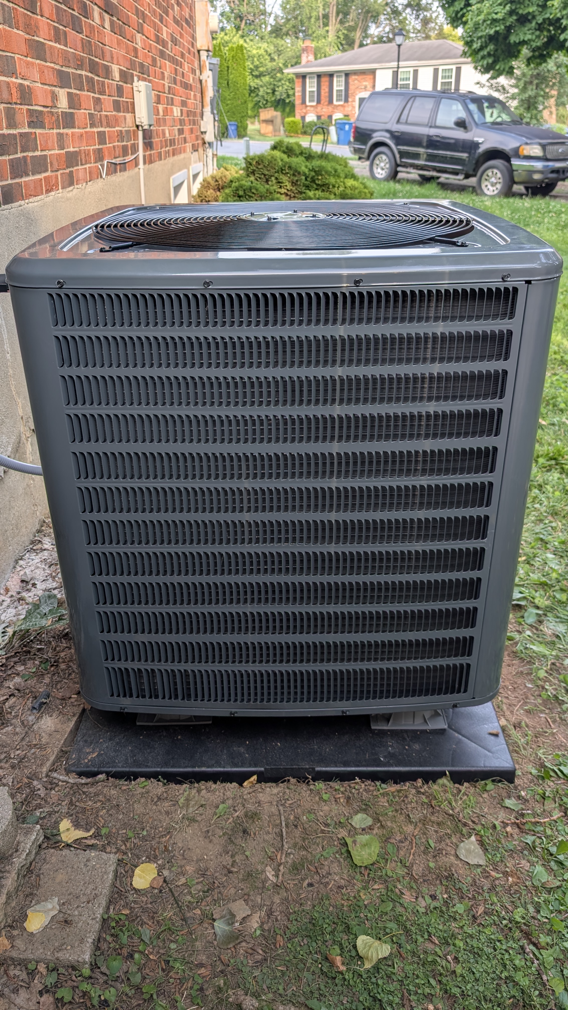New Daikin condenser front view cleanly installed against brick wall