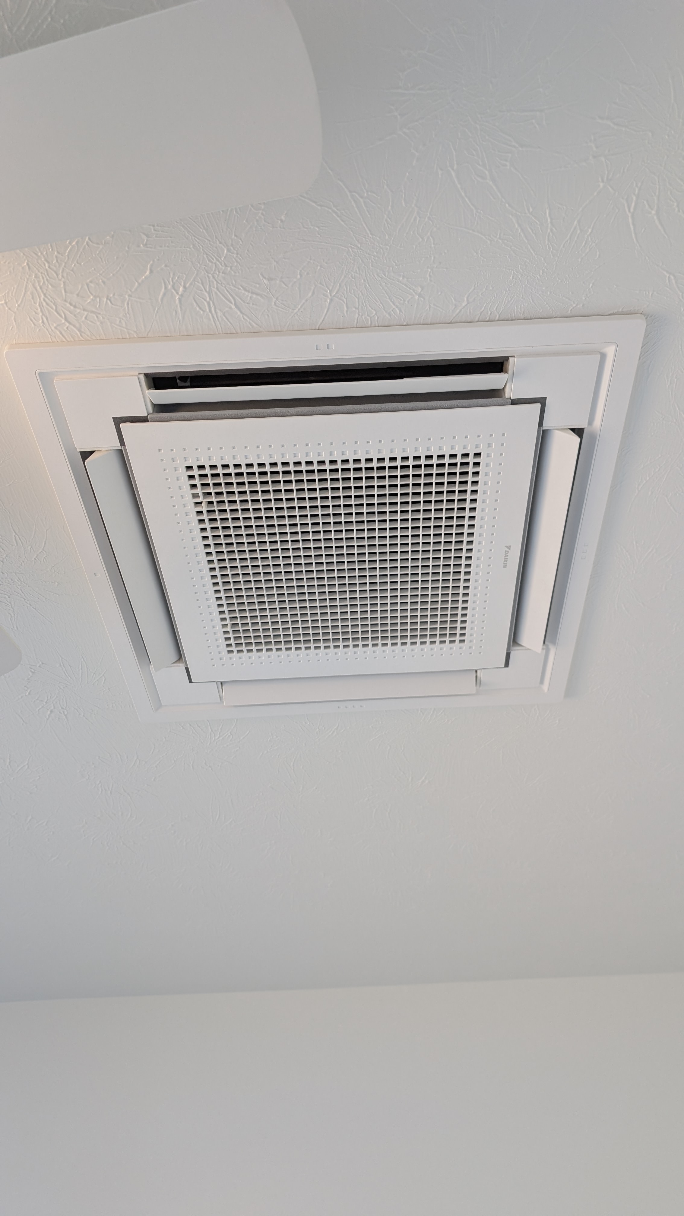 Daikin ceiling cassette mini-split indoor unit fully installed flush in white textured ceiling