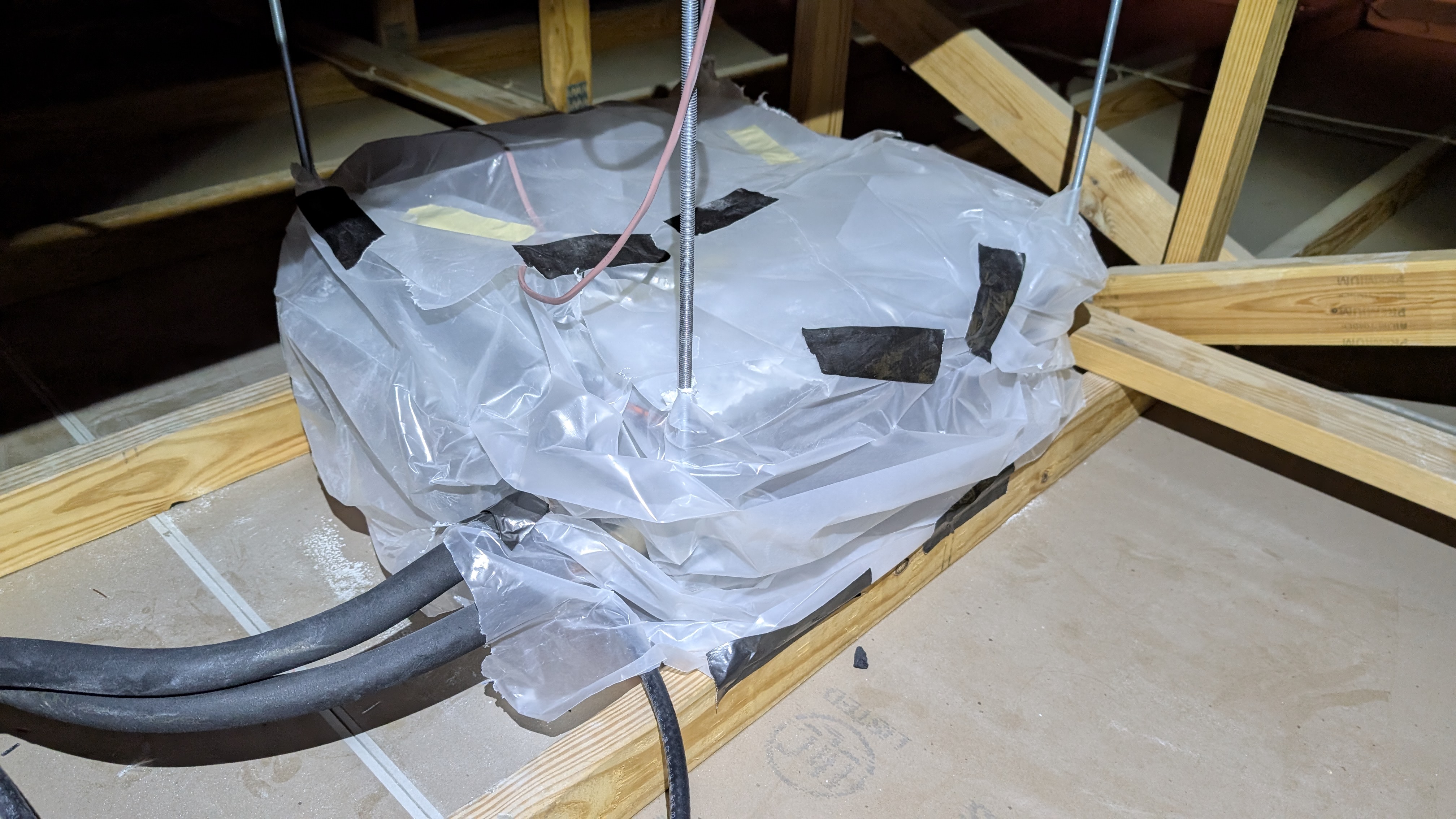 Ceiling cassette mini-split indoor unit wrapped in plastic for protection during finishing work above ceiling