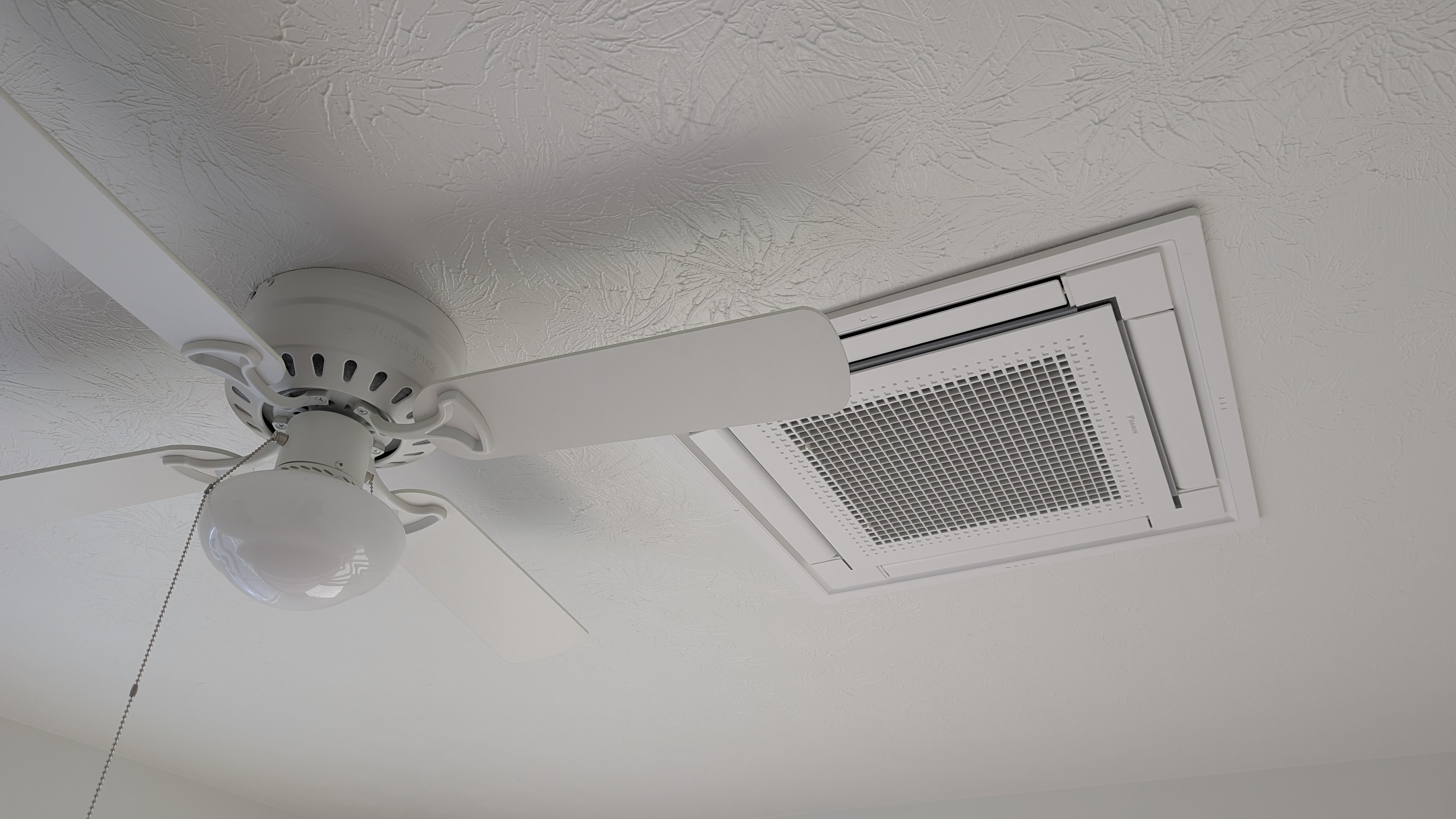 Daikin ceiling cassette mini-split installed in finished living space next to ceiling fan after photo
