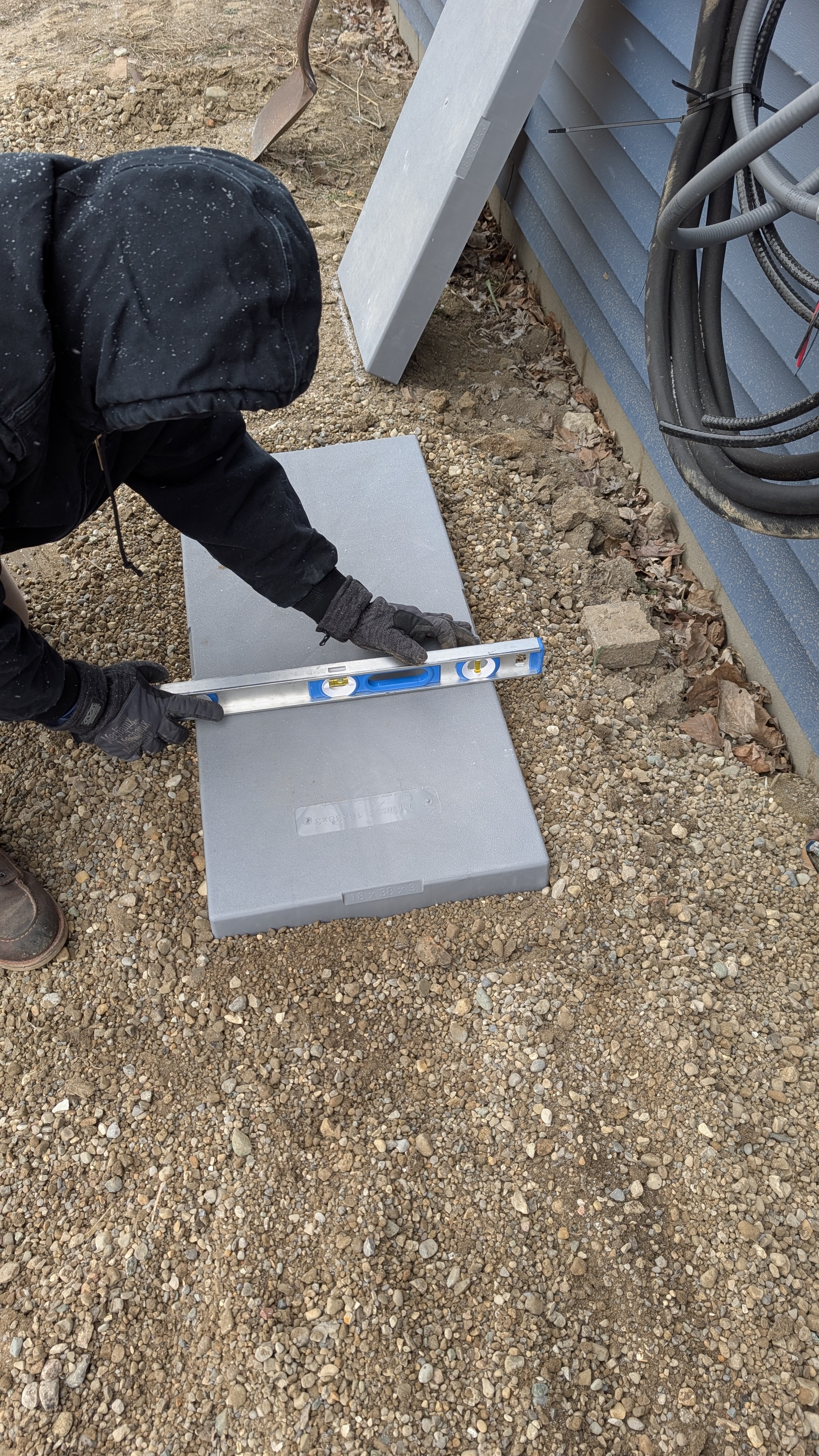 Technician using level to ensure condenser mounting pad is perfectly flat before outdoor unit install