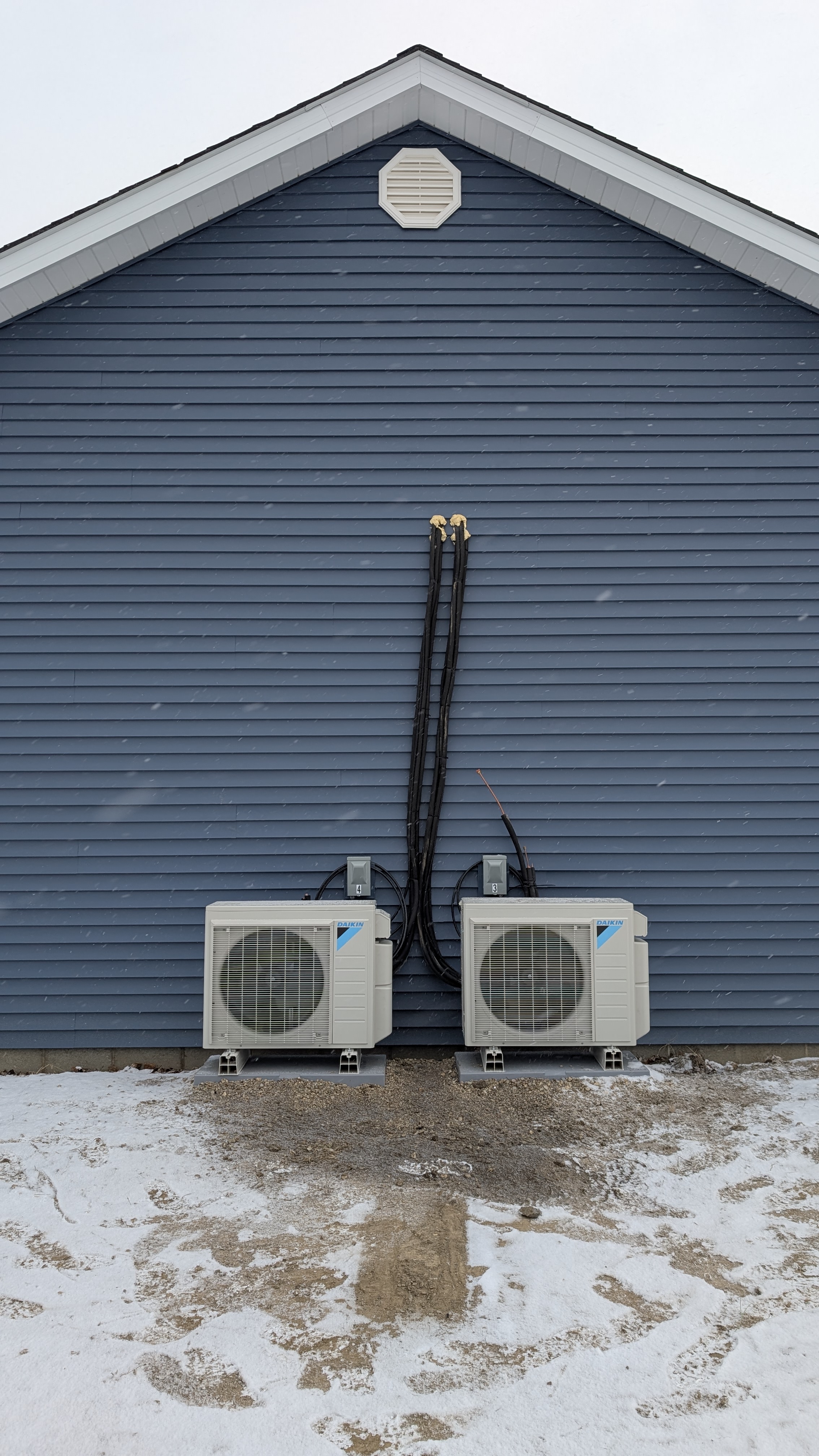 Two Daikin mini-split outdoor condenser units fully installed on concrete pads at new-construction building