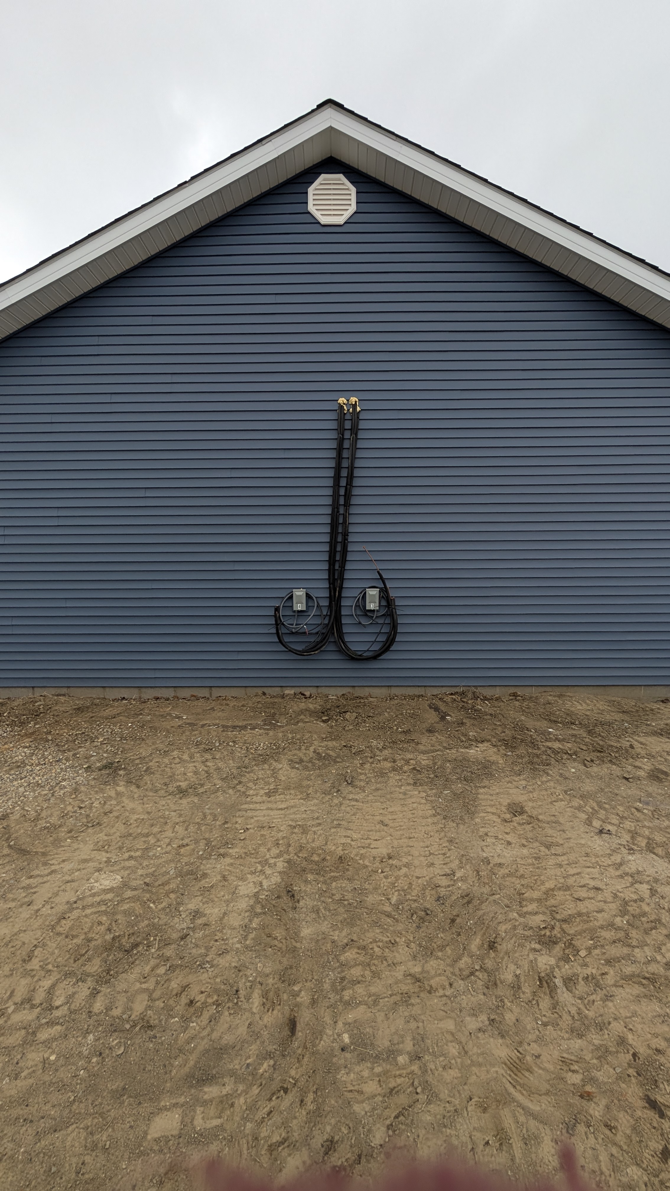 New-construction building exterior showing dual mini-split line-set runs from roofline to ground with two disconnect boxes