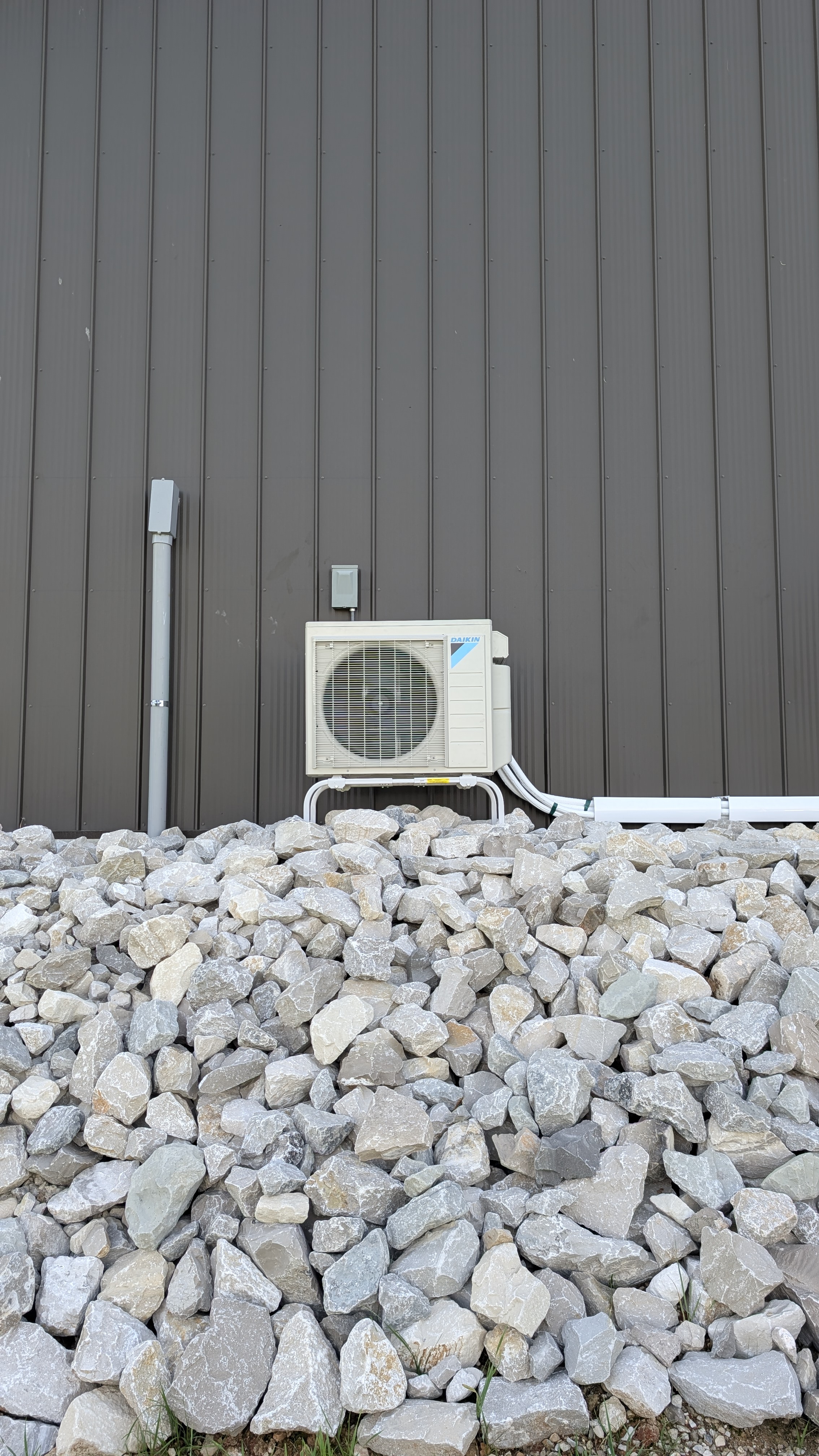 Daikin mini-split condenser with line-set chase and disconnect box mounted on Indiana pole barn