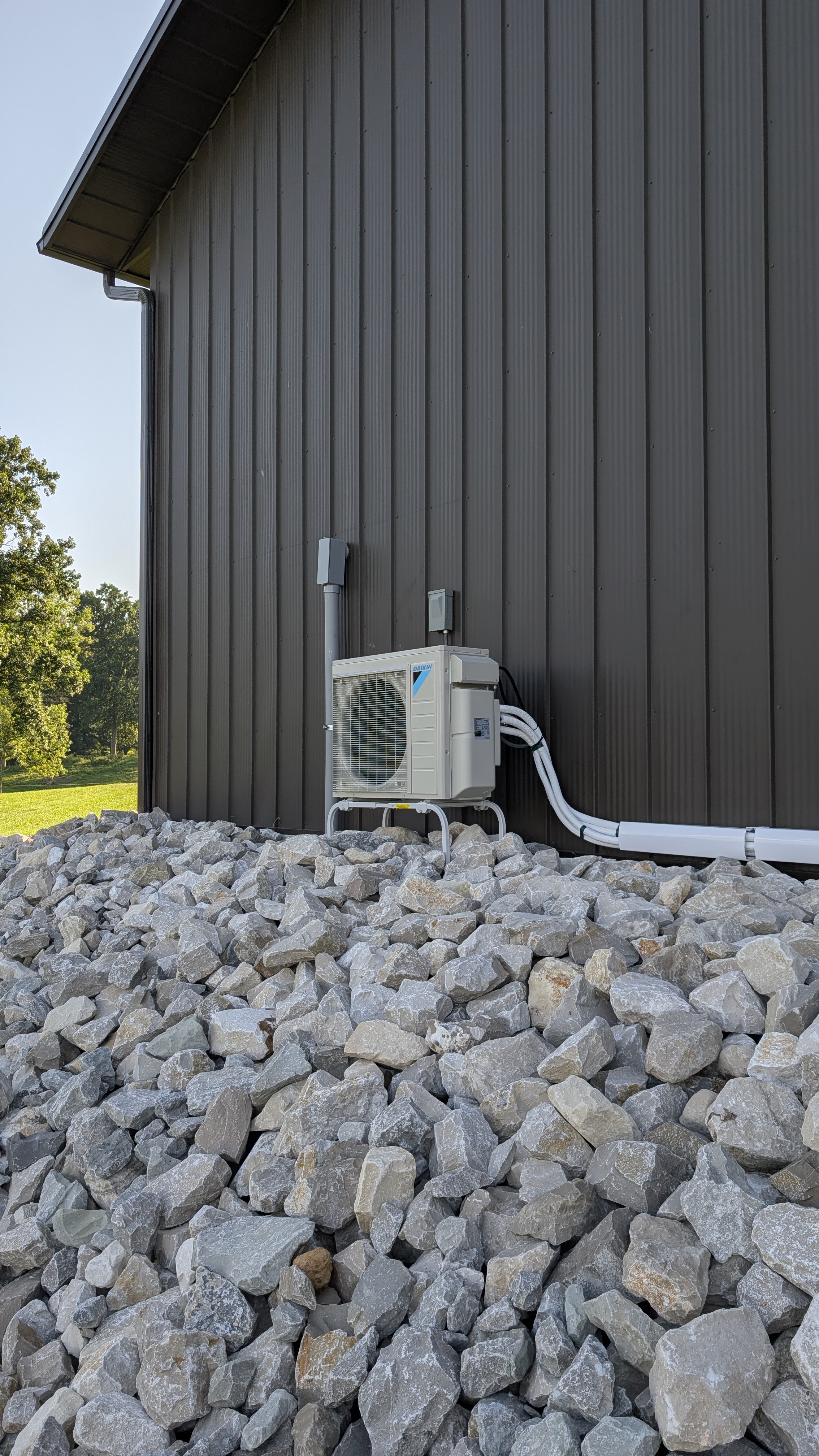 Daikin mini-split outdoor condenser installed on pole barn corner with rural Indiana landscape visible