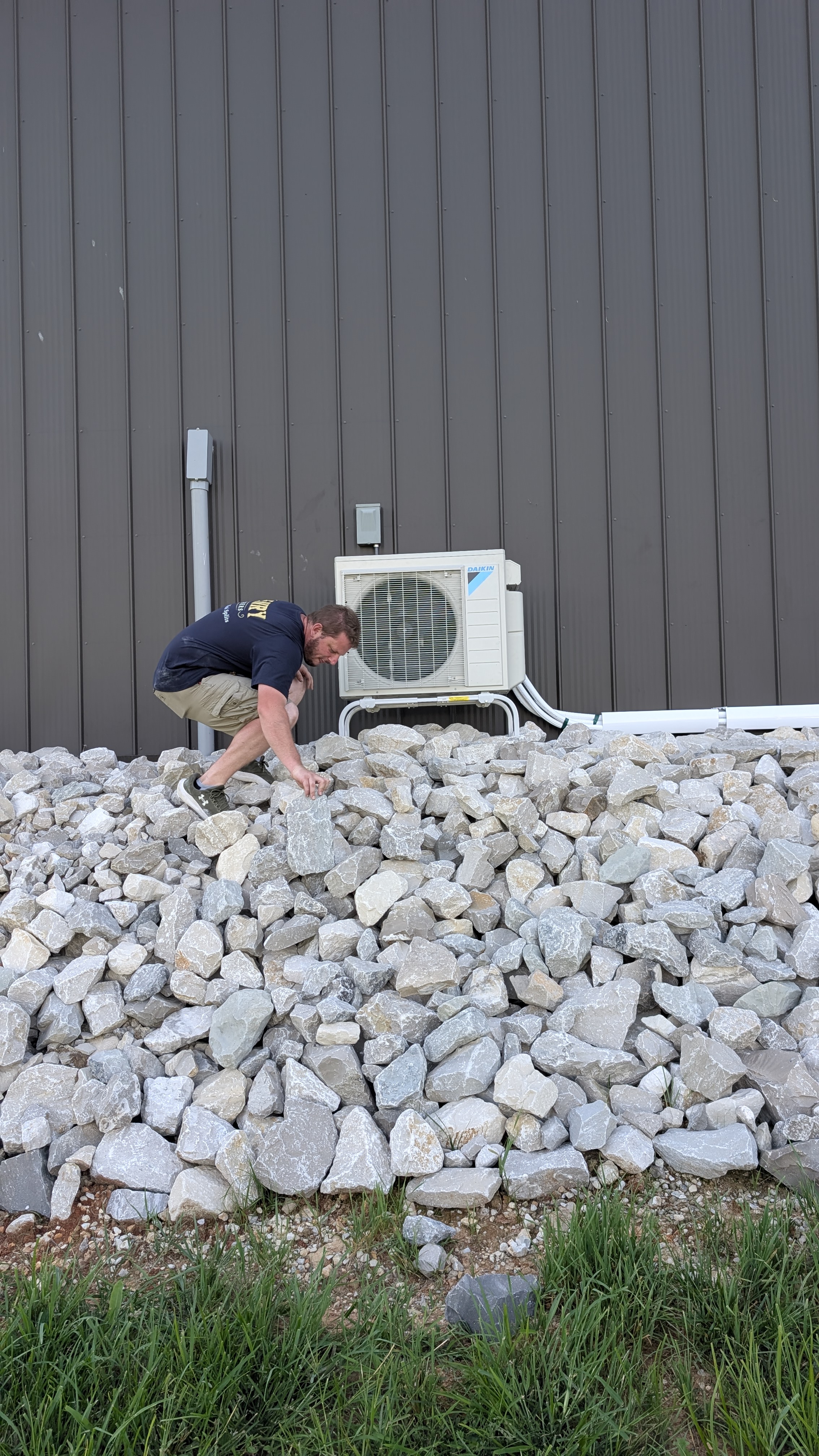 Henry Brothers technician climbing rock bed during Daikin mini-split install at Indiana barn