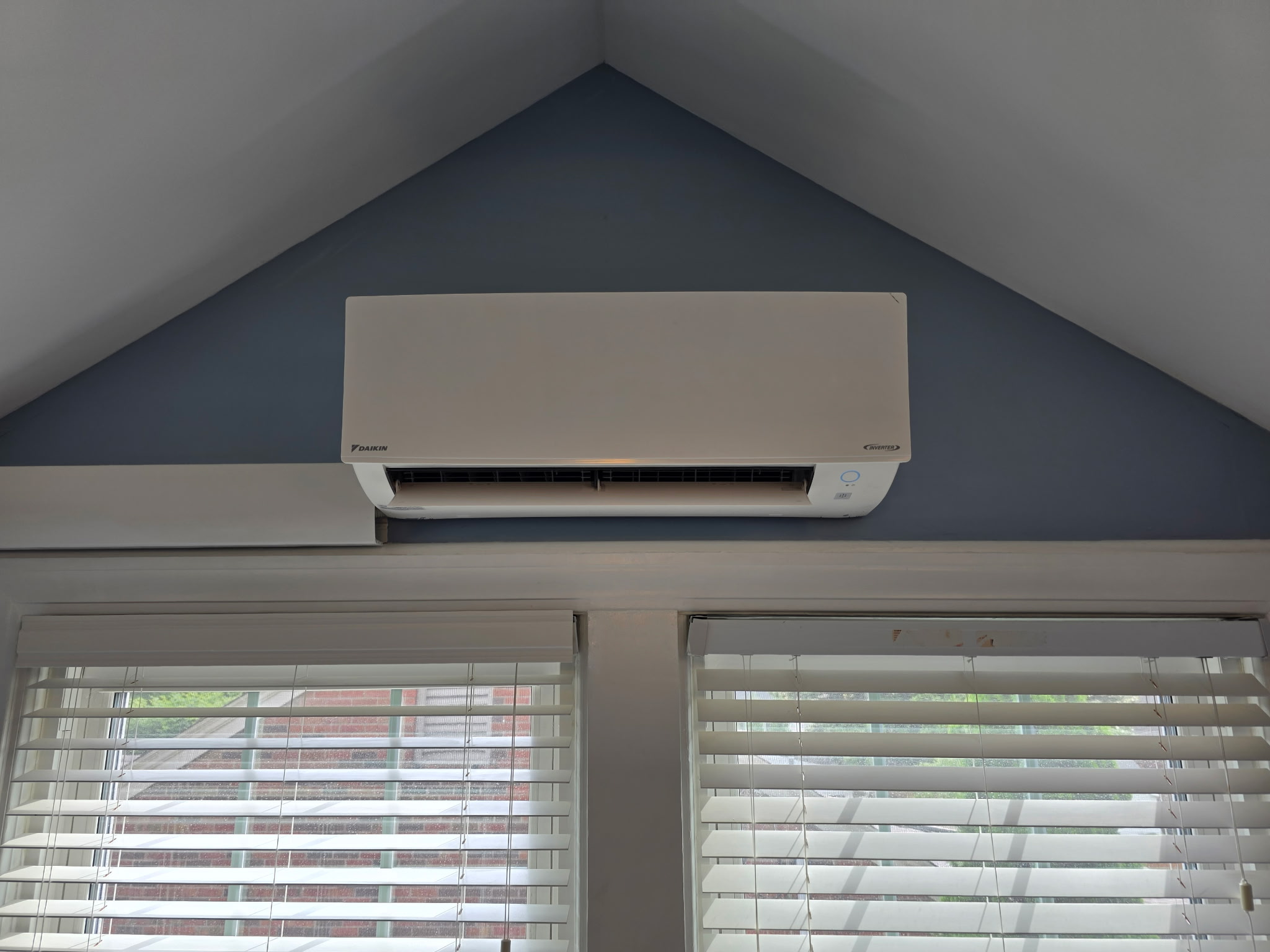 Daikin mini-split indoor unit mounted under vaulted ceiling between two windows in living space