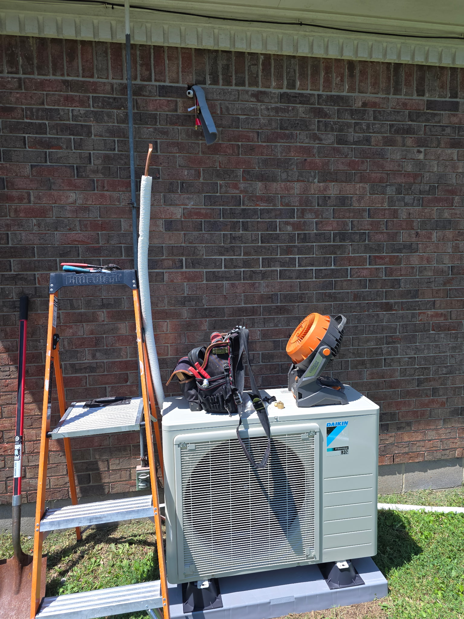 Daikin mini-split outdoor condenser unit on pad with ladder and tools at job site southern Indiana