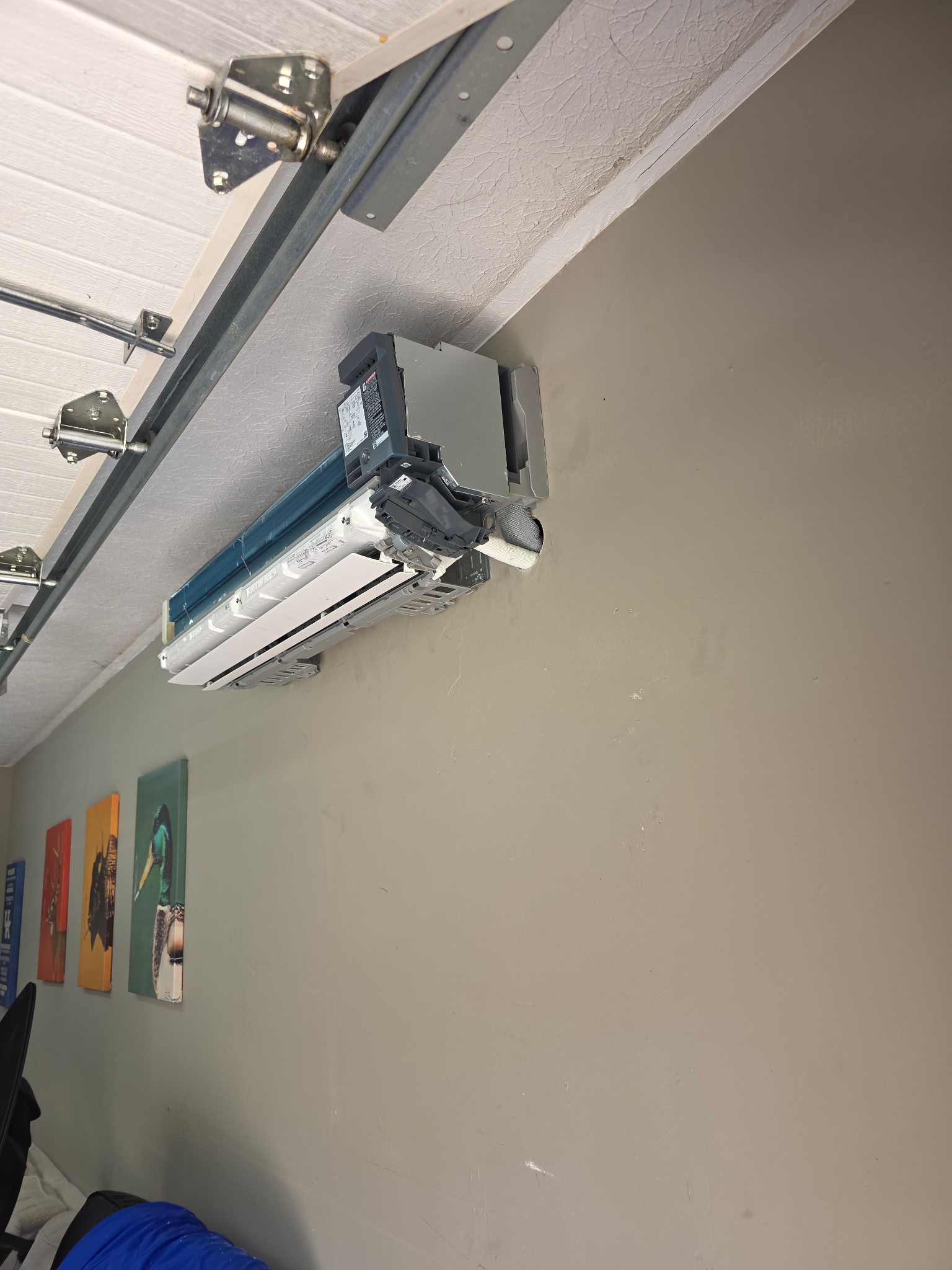Mini-split indoor head unit open exposing evaporator coil during garage wall installation