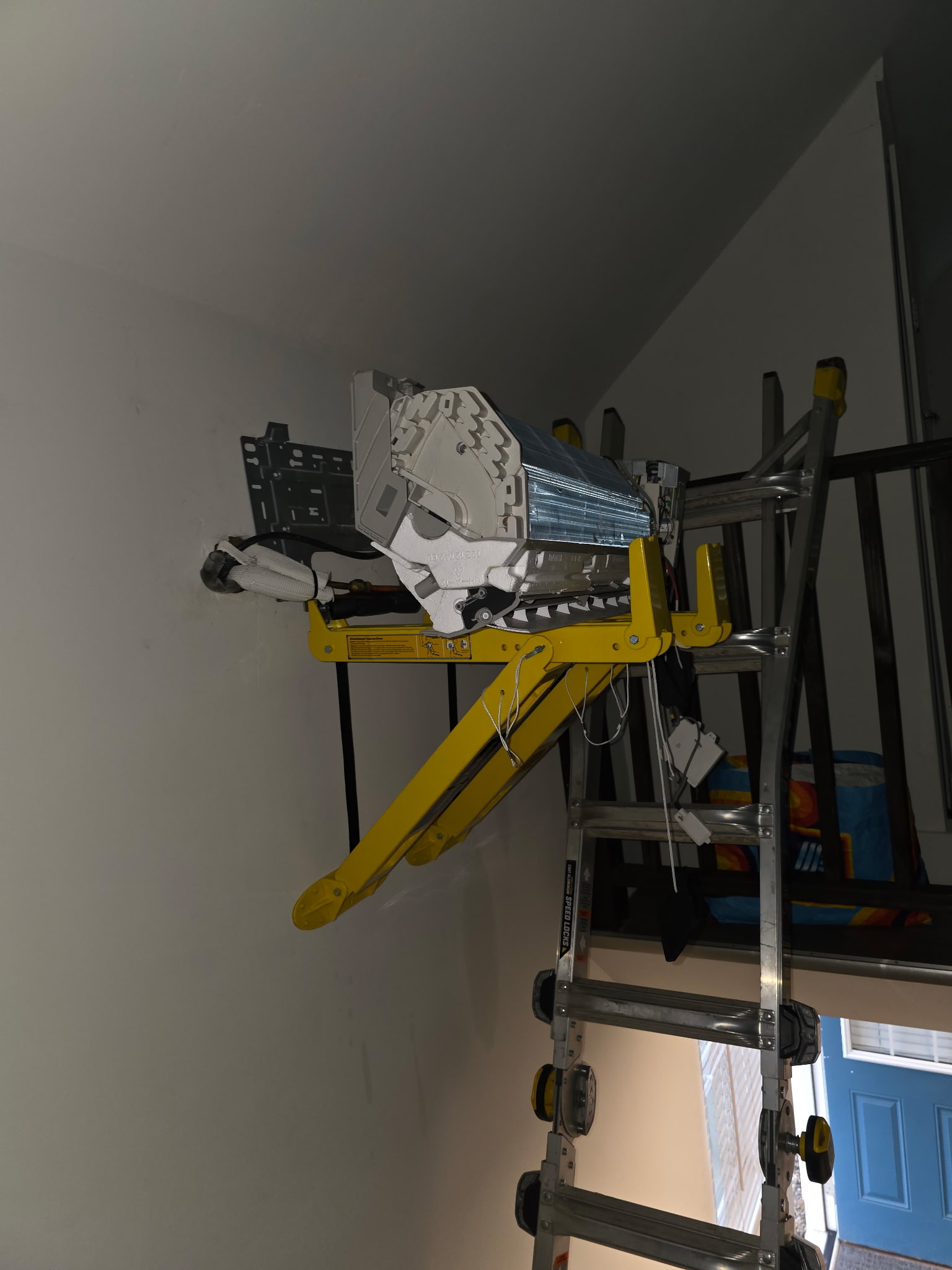 Mini-split indoor unit being positioned at high wall mount using equipment lift during installation